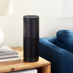 A black speaker sitting on top of a wooden table.