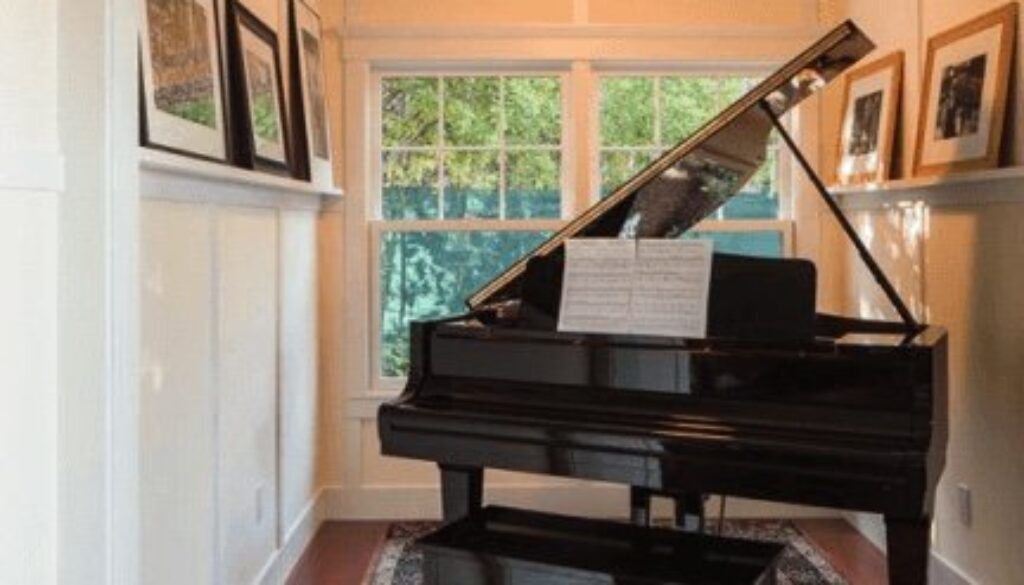 A piano in the middle of a room with pictures on it.