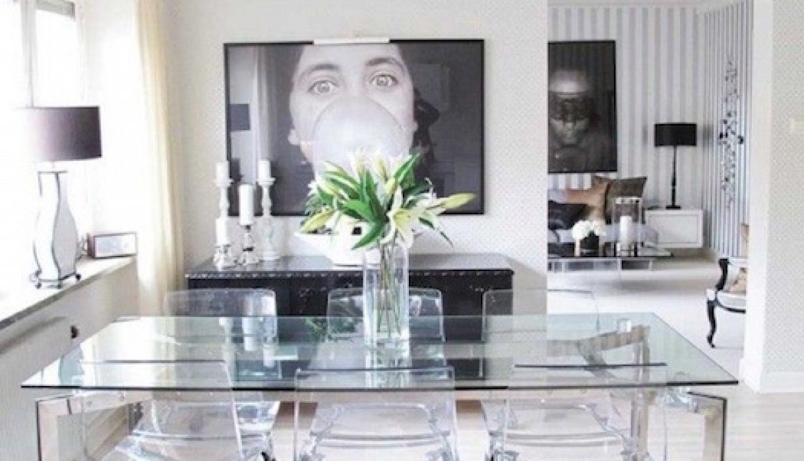 A dining room table with clear chairs and black rug