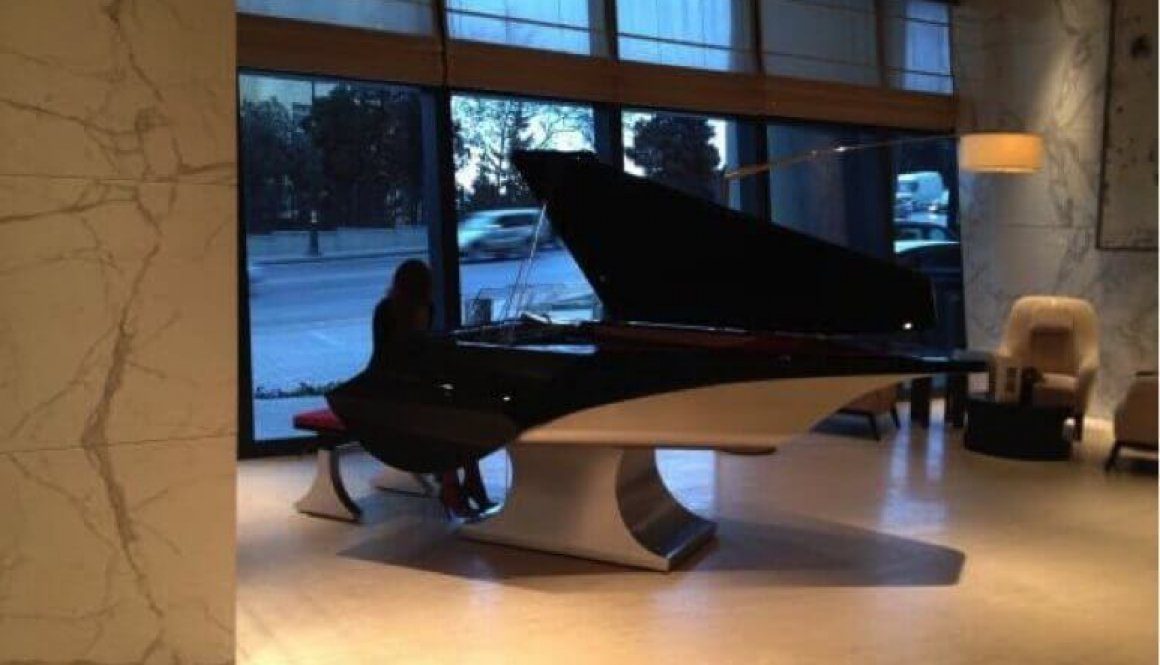 A person sitting on top of a piano in front of a window.