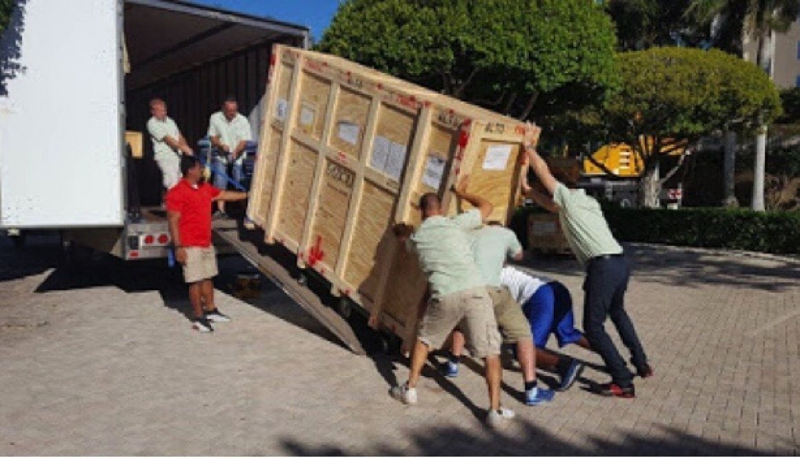 A group of people moving boxes on top of a trailer.