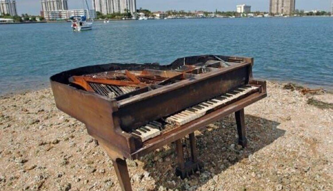 A piano sitting on top of a sandy beach.