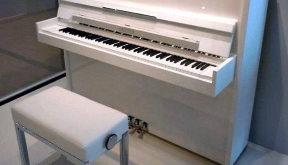 A white piano sitting in front of a wall.