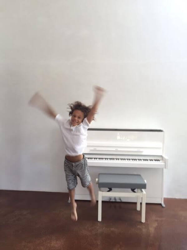 A new student overjoyed with her white Schimmel upright purchased from Euro Pianos Naples.