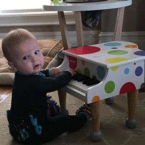 A baby playing with a toy piano on the floor