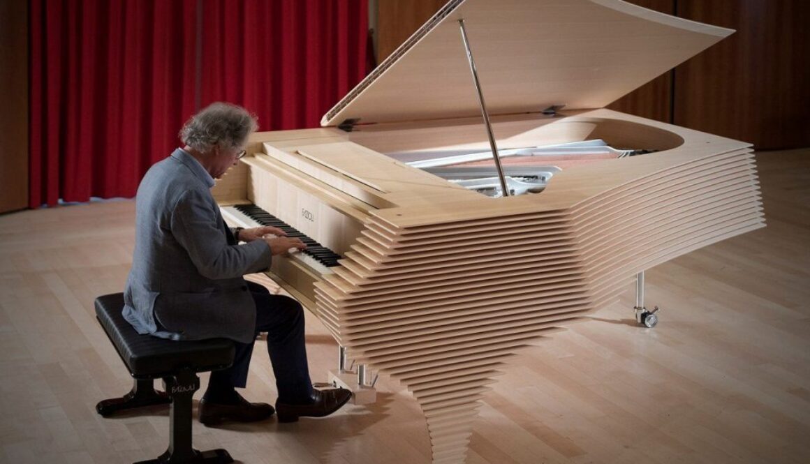 A man playing the piano in front of a red curtain.