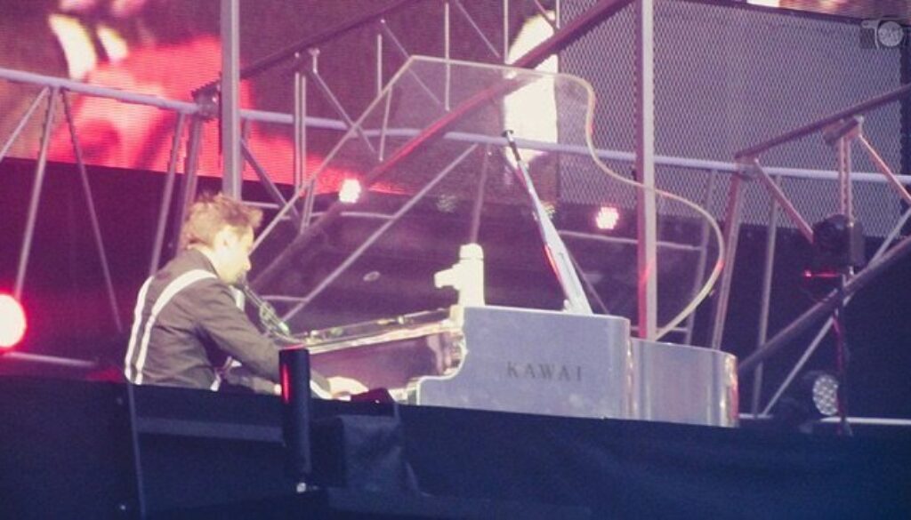 A person sitting at the top of a stage with a piano.