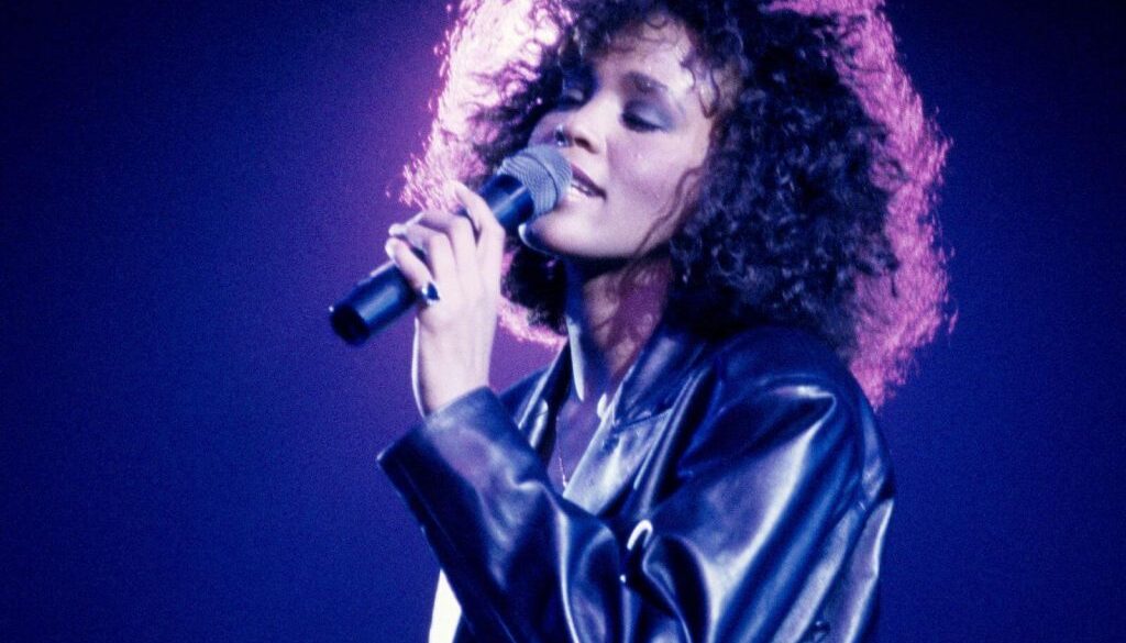 A woman with curly hair is singing into a microphone.