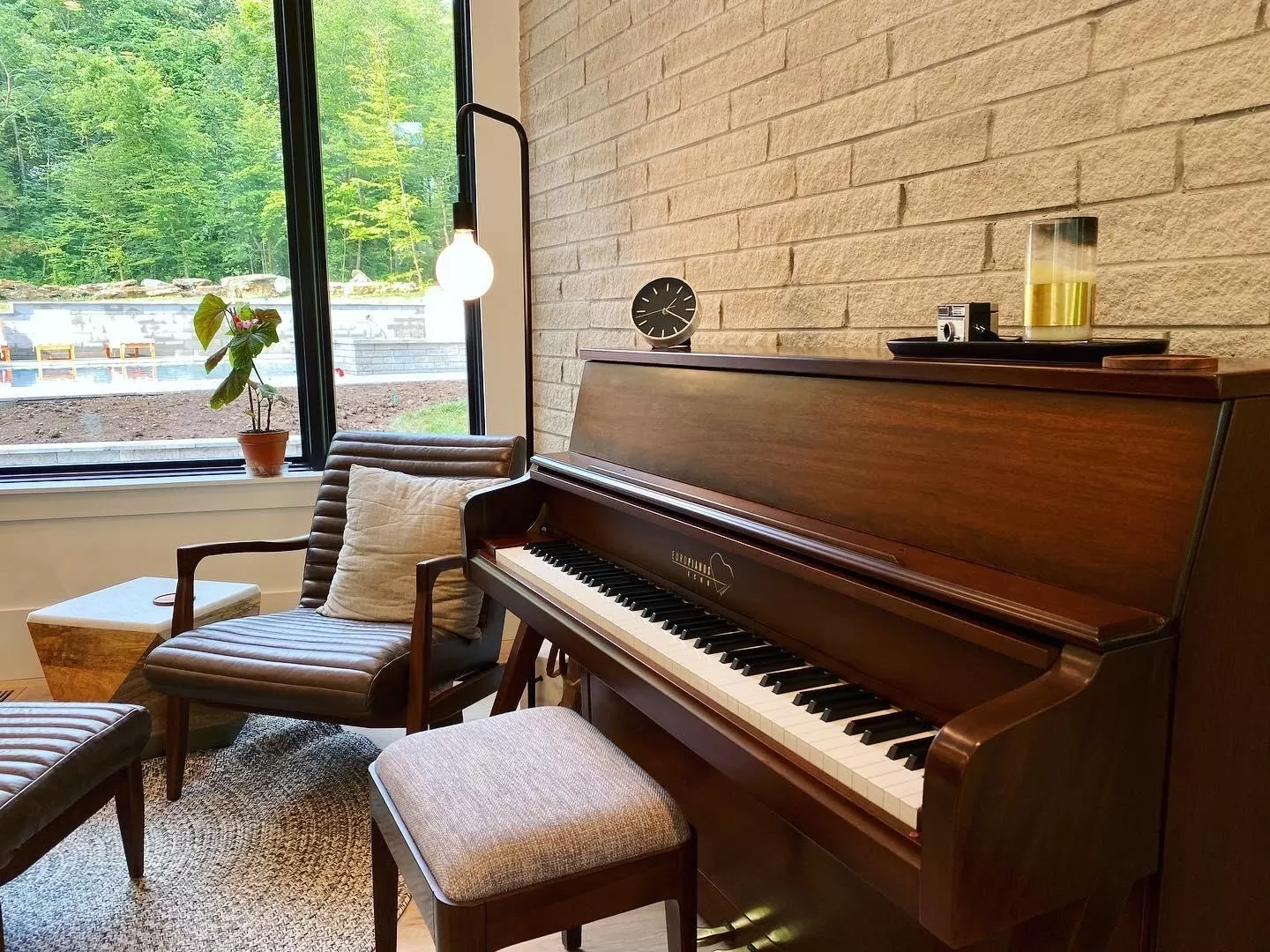 A close up of the piano keys on a Europianos Echo mid century modern upright piano in walnut finish in a cozy living room setting.